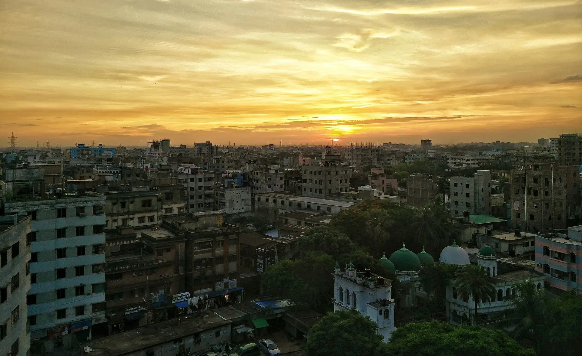 The sun setting over the rooftops and mosque domes of Dhaka